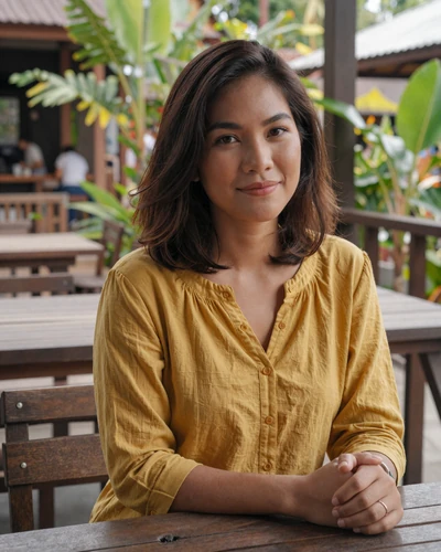 Kanya, 25, Thai woman at outdoor Chiang Mai cafe with tropical plants